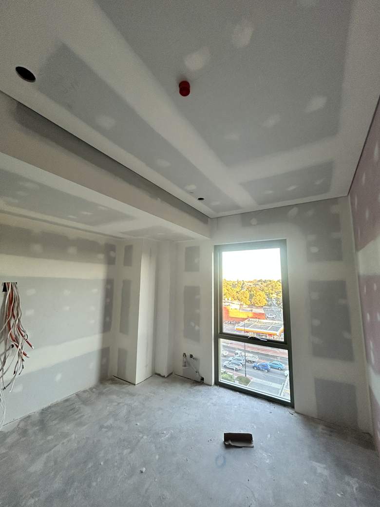 Apartment interior with set ceilings, bulkheads and flushed plasterboard linings.