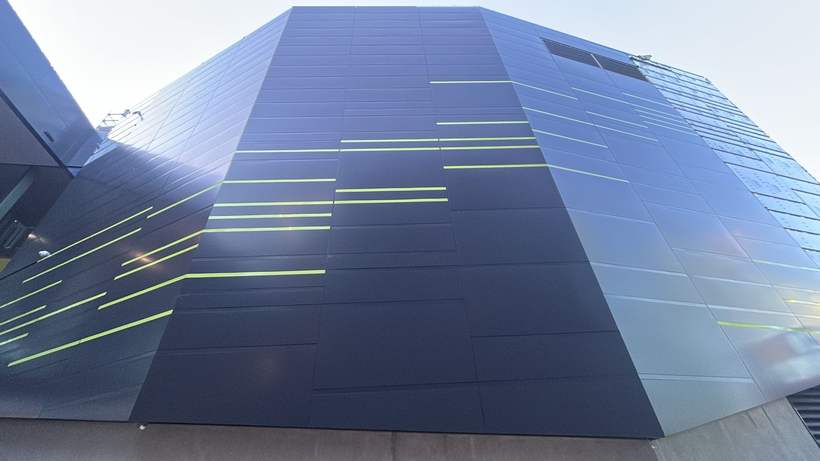 Aluminium composite panel façade with contrast reveals against a dusk sky.