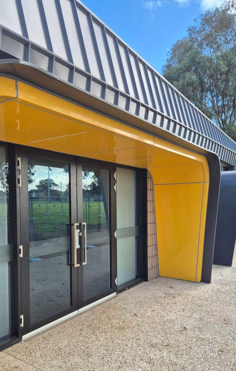 Yellow curved aluminium shroud wrapping the pavilion entry.