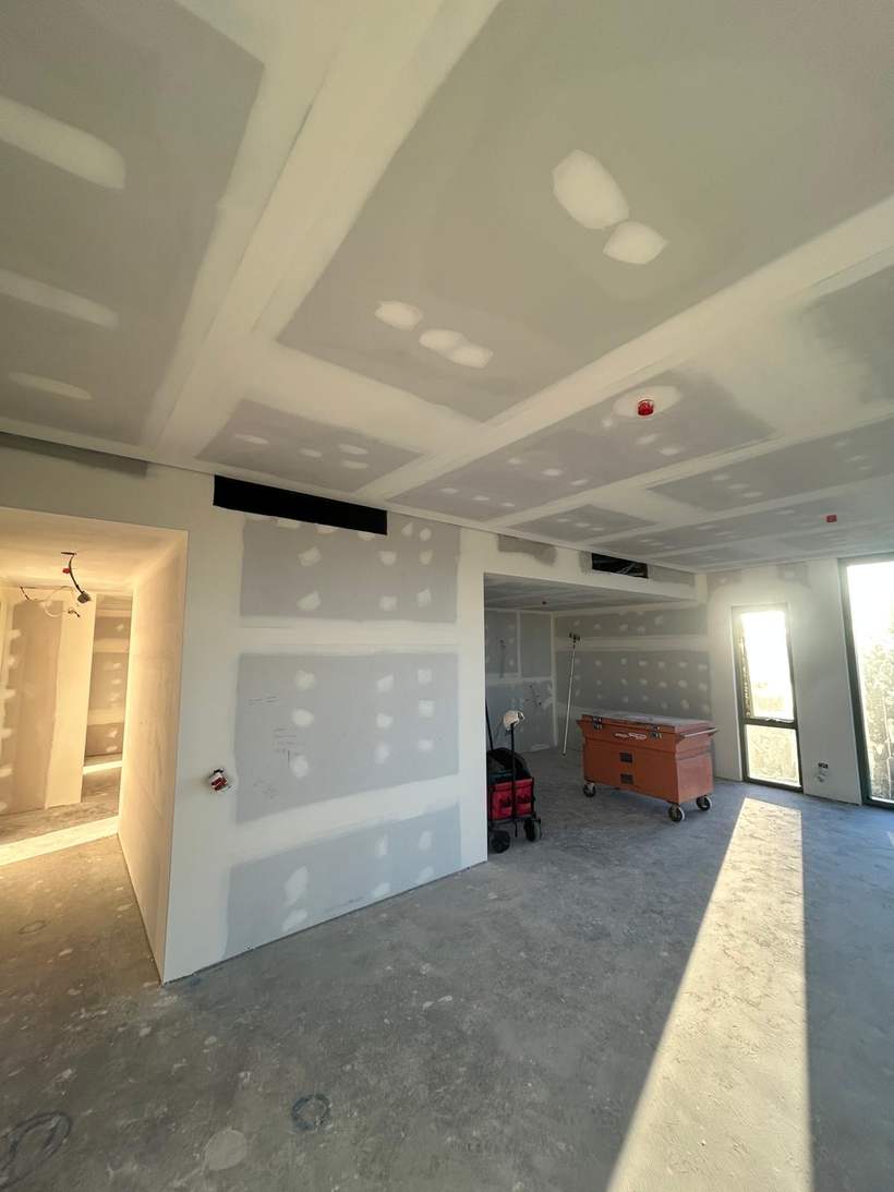 Open plan apartment interior with flushed walls and set ceilings.