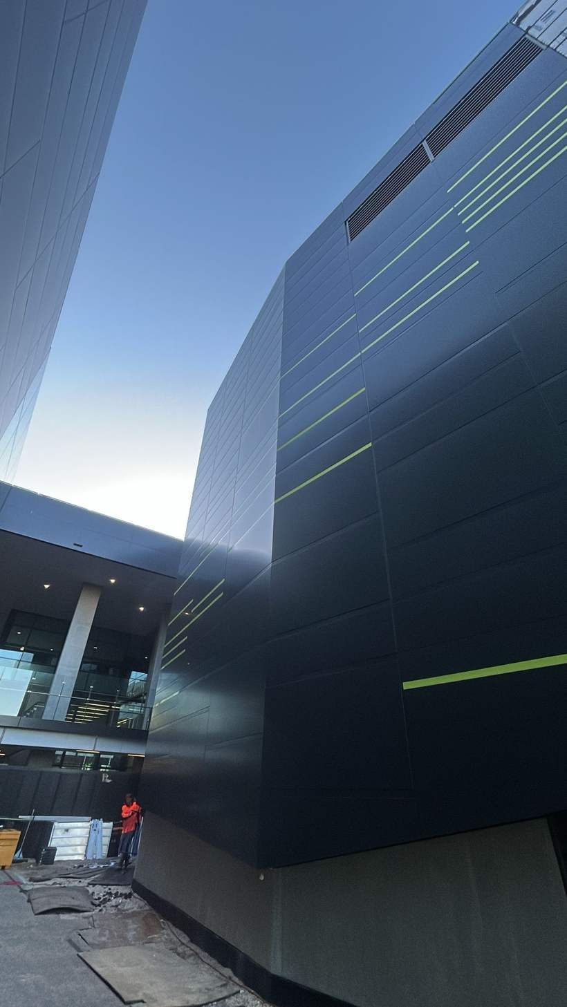 Reclad elevation at dusk with a worker at the base for scale.