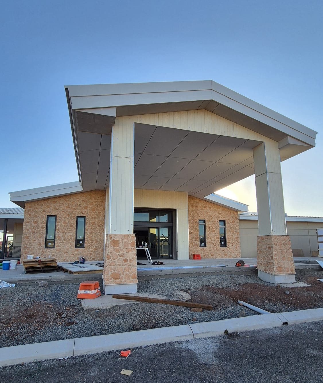 Completed clubhouse entry canopy with CFC-clad columns, soffit and fascia, stone cladding to walls and piers.