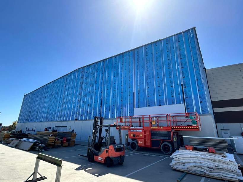 Elevation wrapped in blue breather membrane with vertical top hats fixed over it.