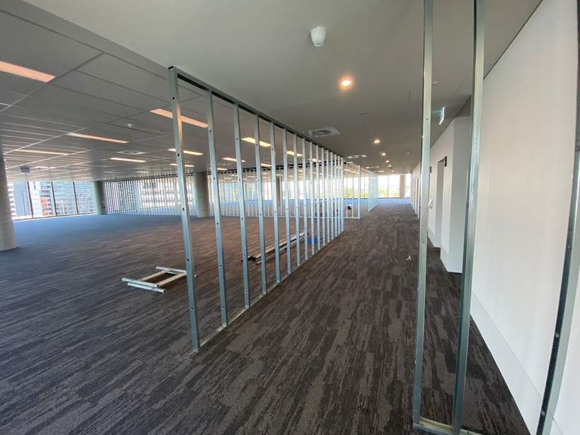 Steel stud framing between finished ceiling and carpeted floor.