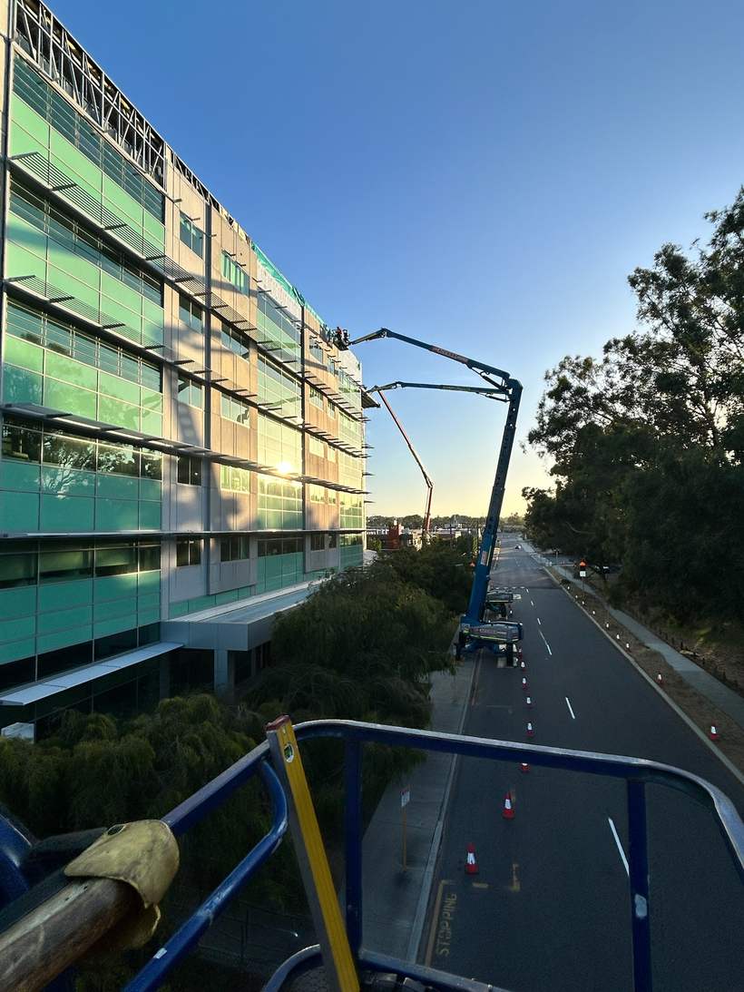 Crew working from an elevated work platform on the building façade at sunrise.
